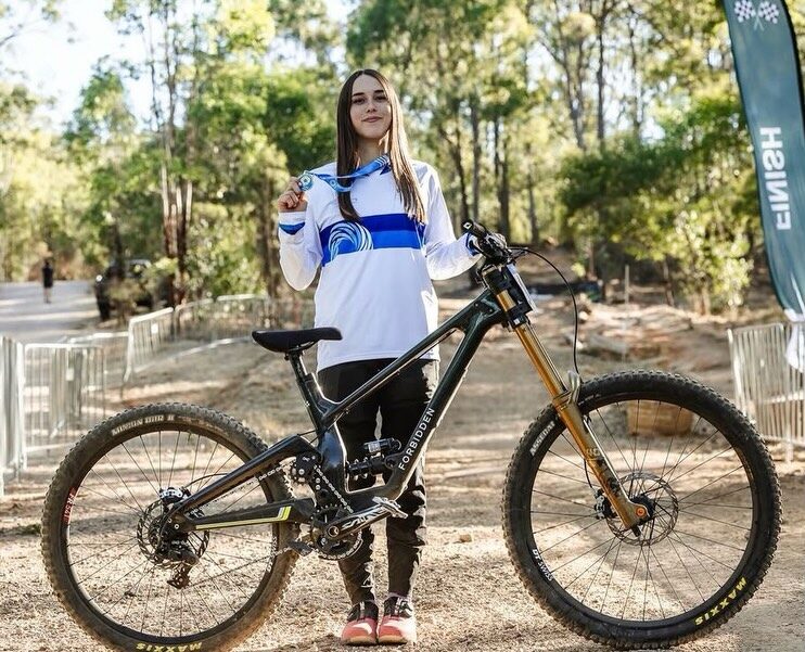 Industrial Fitness ambassador Indy Deavoll holding her medal at a downhill mountain bike race