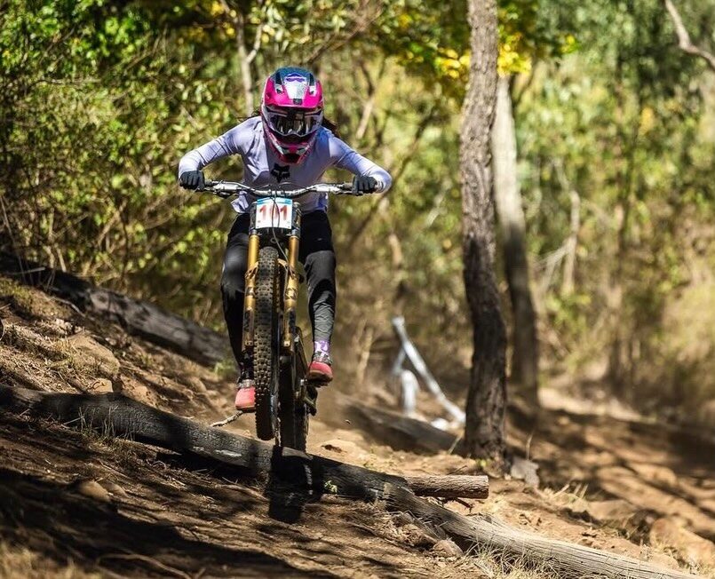 Indy Deavoll racing downhill mountain bike on a forest trail